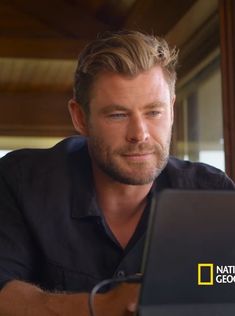 a man sitting in front of a laptop computer looking at the screen with an intense look on his face