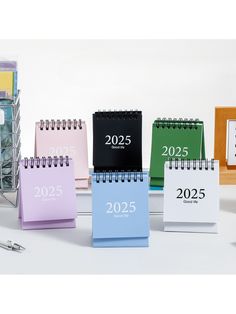 several calendars with numbers on them sitting in front of a stack of office supplies