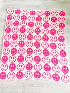 a pink and white towel with smiley faces on it sitting on top of a wooden table