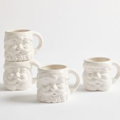 three white ceramic mugs with faces and beards on the sides, one is empty