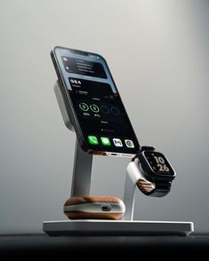 an apple watch and cell phone charging on a stand with the dock attached to it