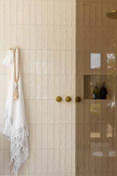 a white towel hanging on the wall next to a shower door with gold handles and knobs