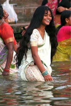 a woman is sitting in the water with other people around her and smiling at the camera