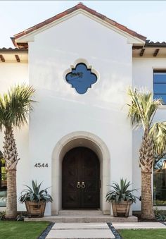 a white house with palm trees and potted plants