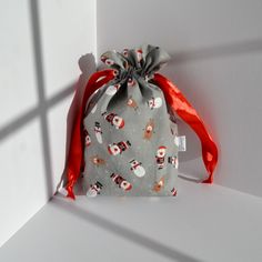 a small drawsack bag with red ribbon tied around it on top of a white surface