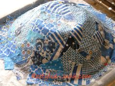 a blue and white patchwork hat sitting on top of a table covered in fabric