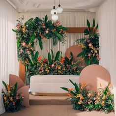 an arrangement of flowers and greenery on the back of a couch in a room