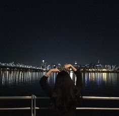 a woman is looking out over the water at night