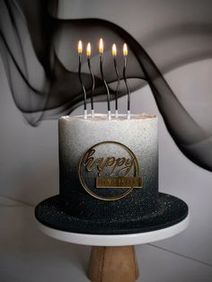 a black and white birthday cake with lit candles on it's top that says happy birthday