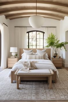 a large bed sitting in a bedroom next to a window with white drapes on the windowsill