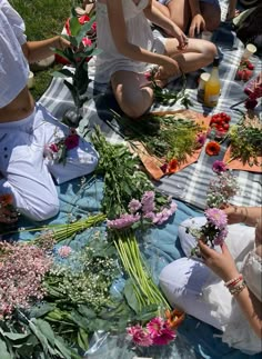 several people sitting on the ground with flowers in their hands