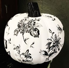 a white pumpkin decorated with black and white flowers