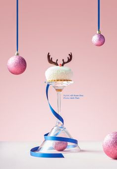 a cake sitting on top of a glass in front of christmas ornaments hanging from the ceiling