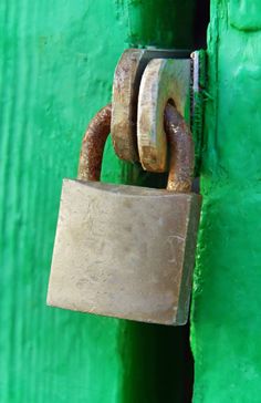 an old padlock attached to a green door