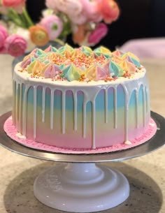 there is a cake with icing and sprinkles on the top that has pink flowers in the background