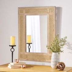 a mirror sitting on top of a wooden table next to a vase with a plant