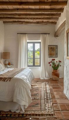 a bedroom with a bed, rug and window in the room that has white curtains