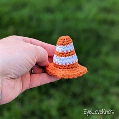 a small crocheted orange and white hat is held in someone's hand