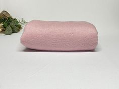 a pink pillow sitting on top of a white table next to a potted plant