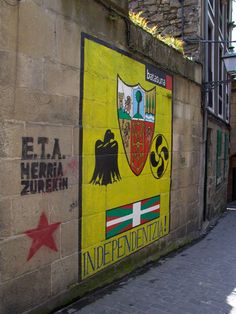 a yellow and red flag painted on the side of a building next to a brick wall