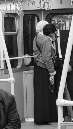 two people standing on a train next to each other