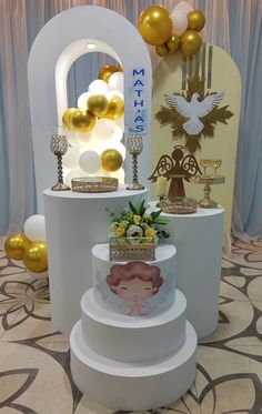 three tiered white cake with gold decorations and balloons in the background at a wedding reception