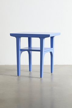 a small blue table sitting on top of a cement floor next to a white wall