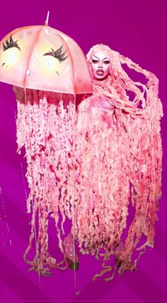 a woman in pink is holding an umbrella with her face painted like a jellyfish