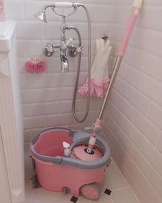 a pink and gray mop bucket in a white tiled bathroom next to a shower head