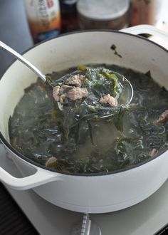 a white pot filled with soup on top of a stove