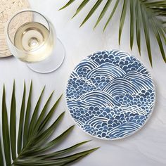 a blue and white plate sitting on top of a table next to some palm leaves