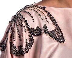 the back of a woman's pink dress with black beads and sequins