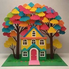 a card with a house and trees on the front that is cut out to look like paper