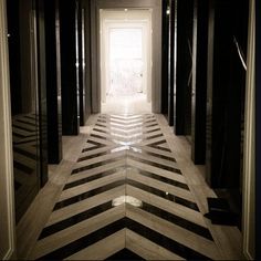 an empty hallway with black and white striped flooring on both sides, leading into the light