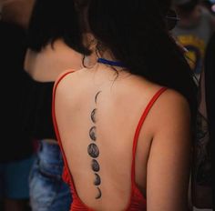 the back of a woman's neck with phases tattooed on her upper and lower back