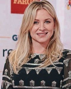 a woman with blonde hair smiling at the camera and wearing a black and white dress