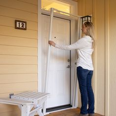 a woman standing in front of a white door holding onto the side of her house