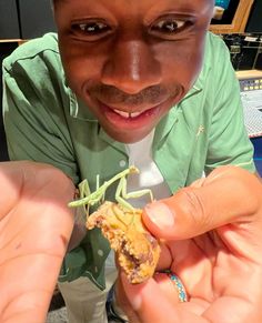 a man holding up a piece of food in his right hand and smiling at the camera