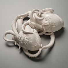 an octopus - like sculpture is shown on a gray surface, with two smaller tentacles attached to it