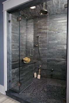 a walk in shower sitting next to a glass door and tiled floored bathroom with gray walls