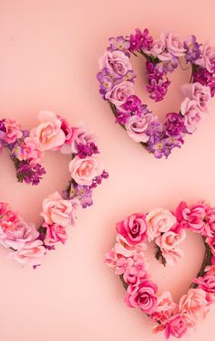 three heart shaped wreaths with pink and purple flowers arranged on the wall next to each other