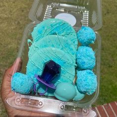 a person holding a plastic container filled with blue cake and frosted teddy bears in it