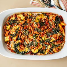 a casserole dish with spinach, sausage and other toppings in it