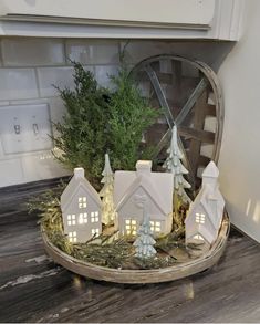 a white christmas village with trees and lights on the top is sitting in front of a window sill