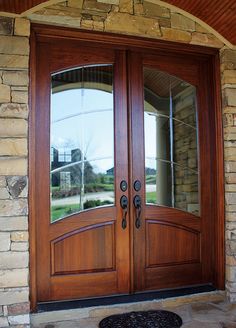 two wooden doors with glass on the front of a house in an area that has stone and brick walls