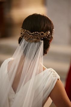 the back of a woman's head wearing a veil with gold beads on it