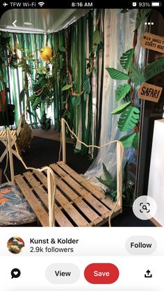 a wooden bed frame sitting in front of a window next to a green plant covered wall