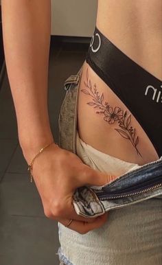 a woman is showing off her stomach tattoo