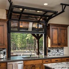 a kitchen with wooden cabinets and an open window over the sink, in front of a black granite countertop