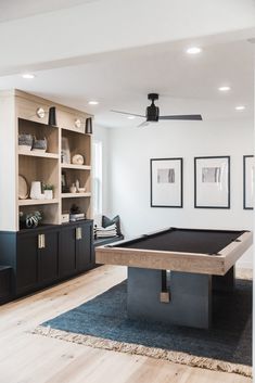 a pool table in the middle of a living room with built - in bookcases